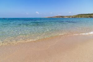 Clear turquoise water meeting golden sand on a sunny beach.