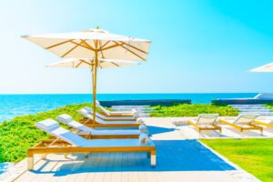 Dashad Blog | Construction, Real Estate & Investment Insights in North Cyprus White lounge chairs with rolled towels under umbrellas on a sunny beach deck overlooking the ocean.