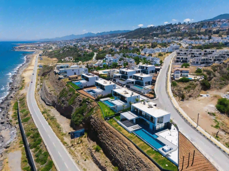 Aerial view of Emerald Villas: TUZLA by NorthernLand in Esentepe, North Cyprus, showing modern villas, green landscaping, and nearby Mediterranean coastline.